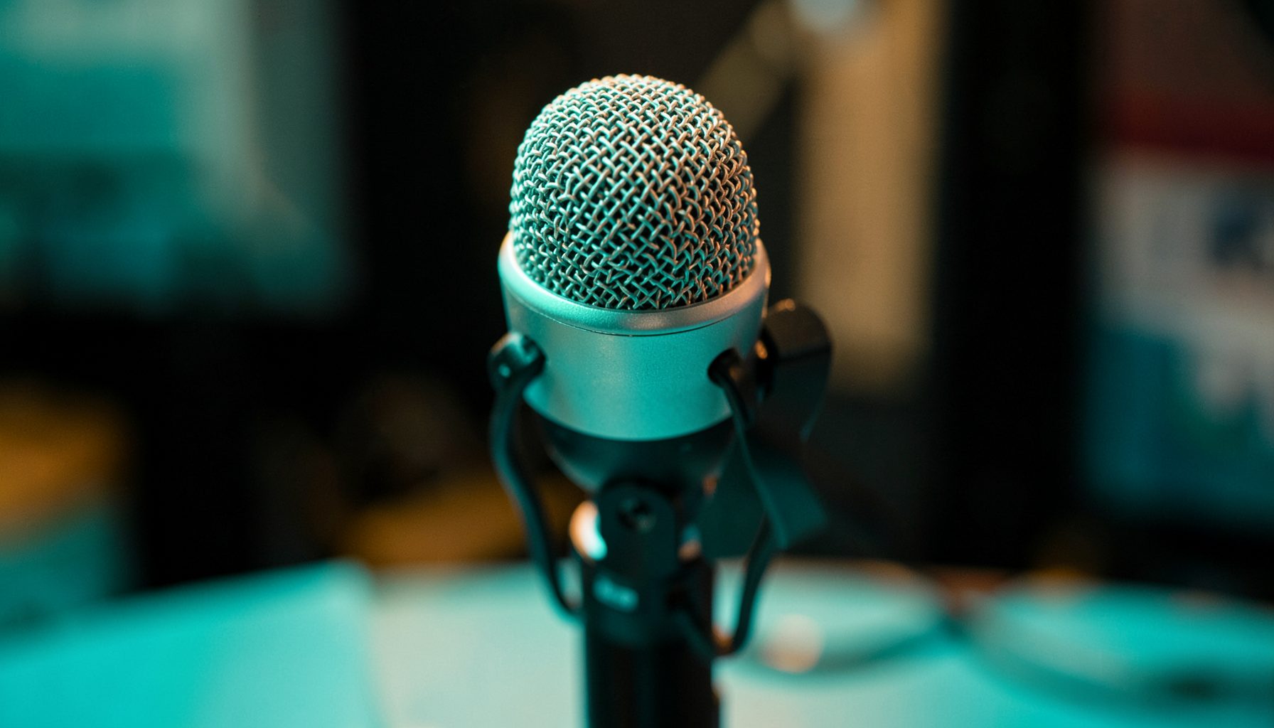 Close-up of a Shure SM7B dynamic microphone on a desk stand, warm studio lighting