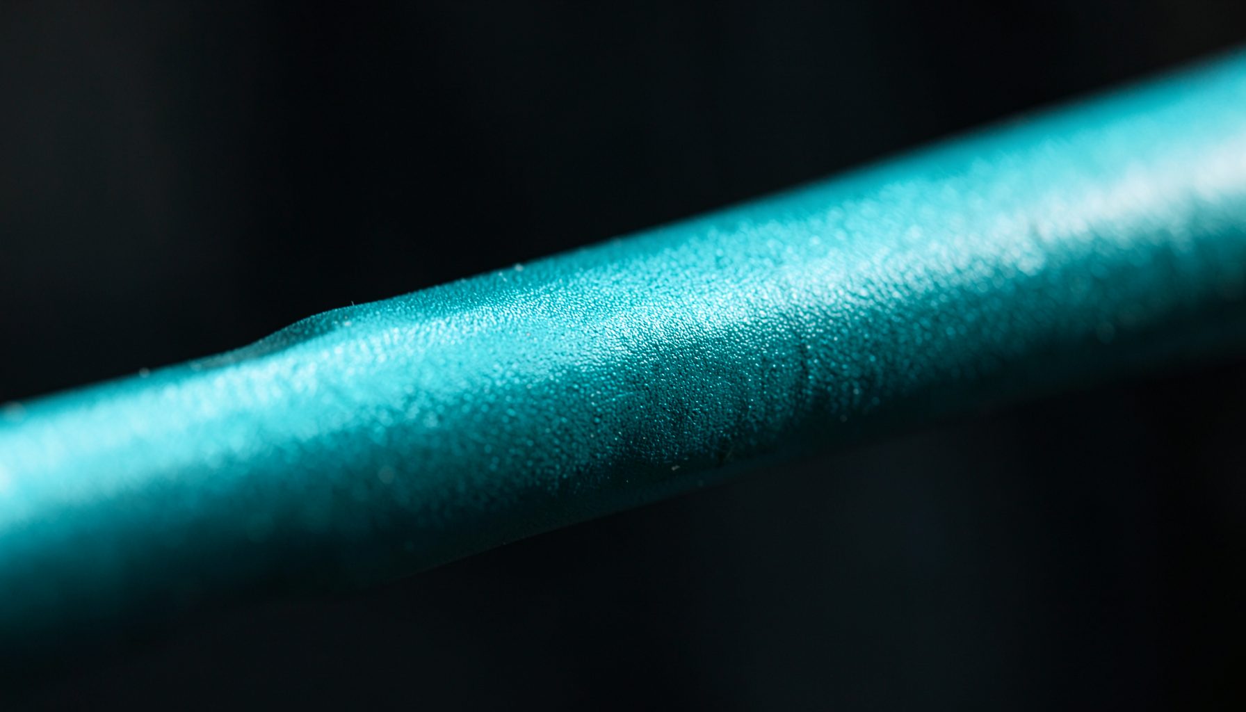 Close-up of a studio microphone boom arm with textured metal finish against a dark blurred background