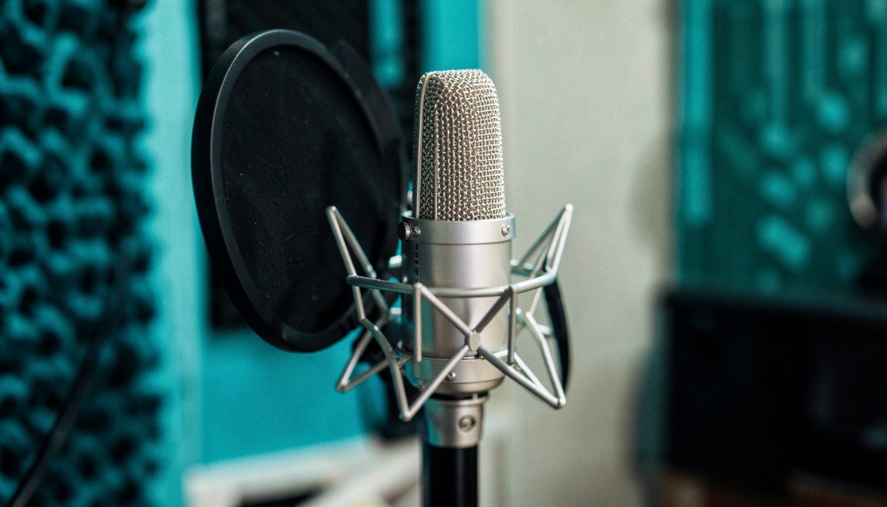 Person recording vocals into a condenser microphone in a home studio, acoustic treatment on walls
