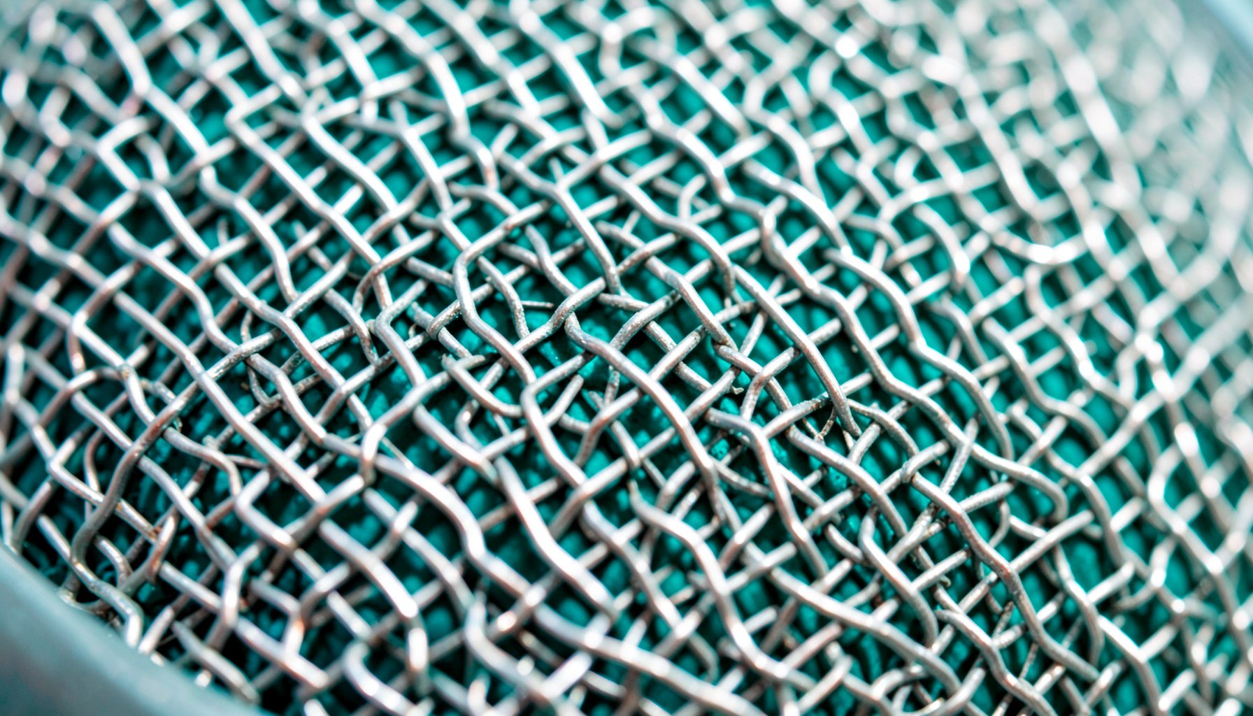 Extreme close-up of a microphone grille mesh texture, metallic silver with fine woven pattern