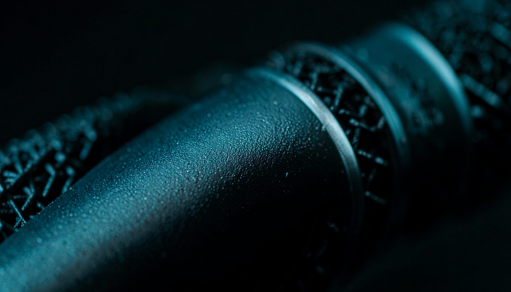 Extreme close-up of matte black microphone body with subtle grain texture, dark studio mood